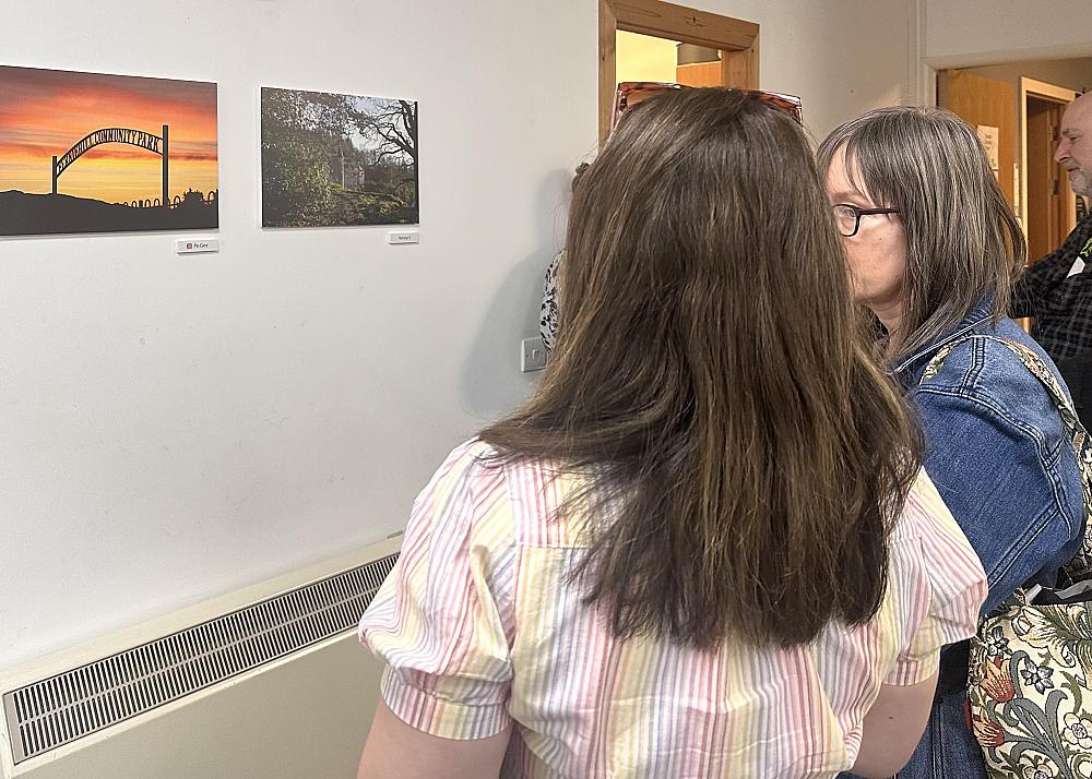Two guests looking at photography images on an inside wall.