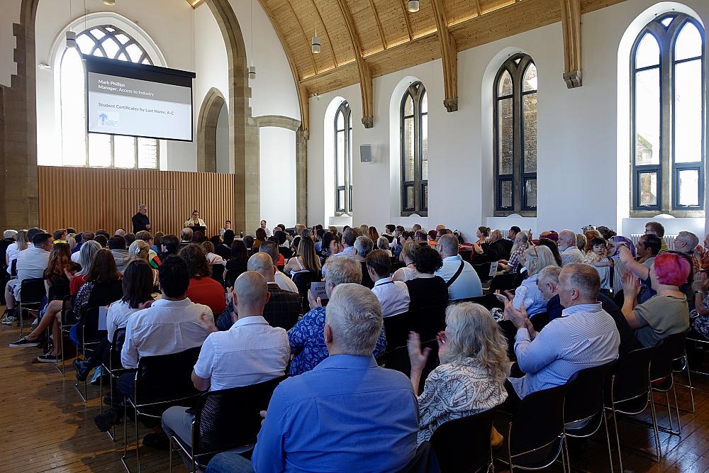 Crowd of people gathered indoors in a hall for an award-giving event.